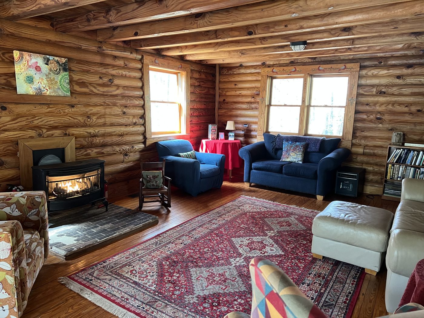The Sacred Grove log cabin interior with a lit fireplace and comfortable seating